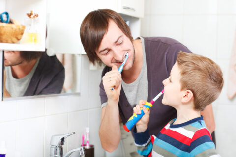 Father and son brushing teeth in bathroom