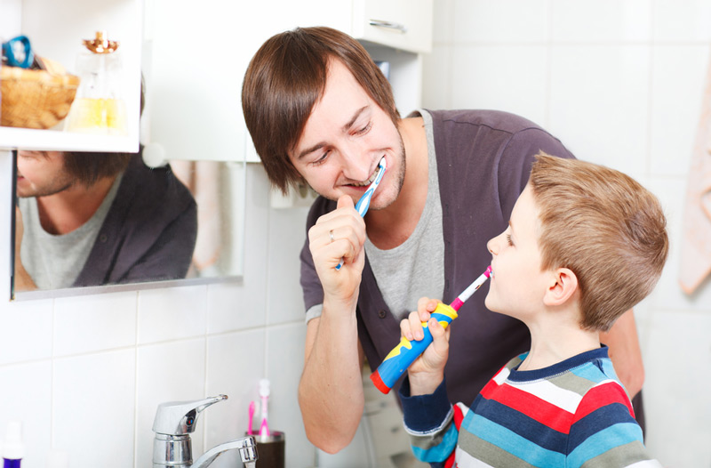 Father and son brushing teeth in bathroom